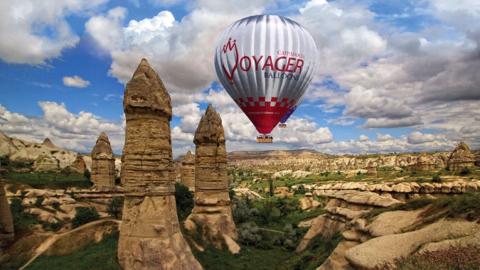 A hot air balloon floating over a picturesque landscape during a deluxe balloon tour.